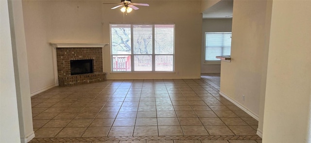 unfurnished living room with ceiling fan, light tile patterned floors, a fireplace, and baseboards