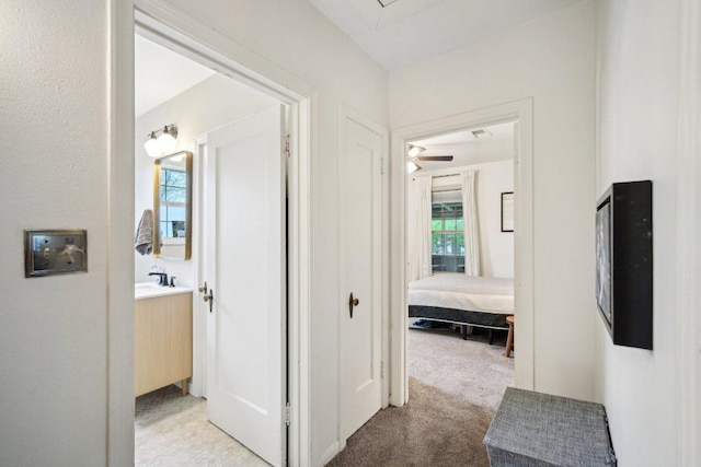 hallway with attic access and light colored carpet