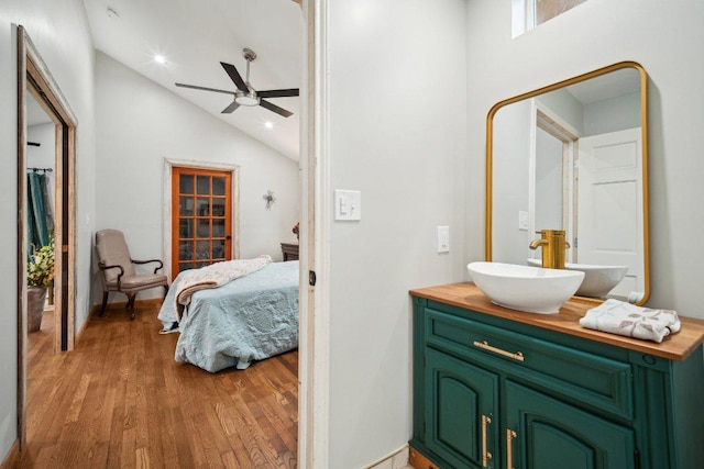 ensuite bathroom featuring ceiling fan, wood finished floors, connected bathroom, vanity, and lofted ceiling