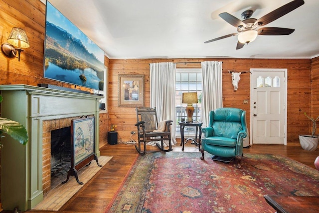 living area featuring wood finished floors, wooden walls, and a brick fireplace
