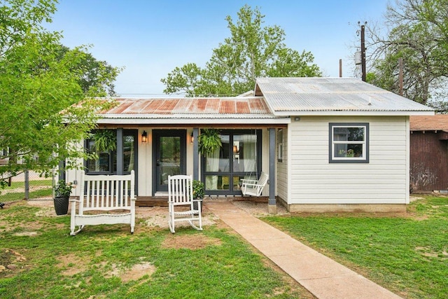 view of front of home featuring metal roof, a front lawn, and a porch