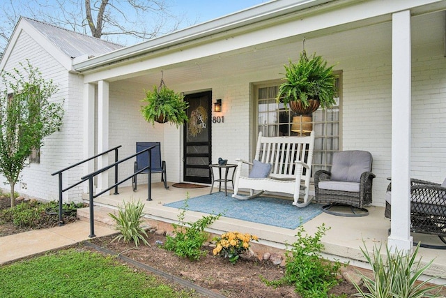 entrance to property featuring covered porch and brick siding