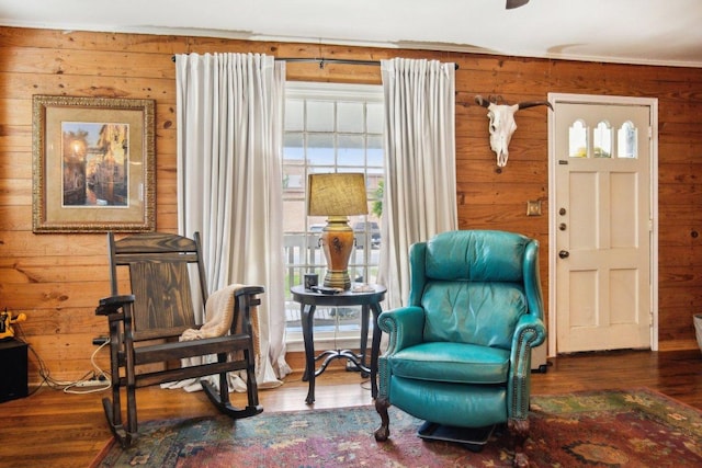 living area with wood finished floors and wooden walls