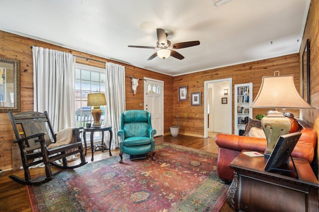 living area featuring wooden walls, a ceiling fan, and wood finished floors