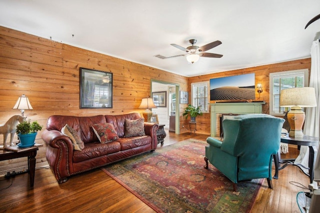 living room featuring hardwood / wood-style floors, a ceiling fan, and wood walls
