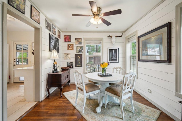 dining area featuring dark wood-style floors, wood walls, and ceiling fan