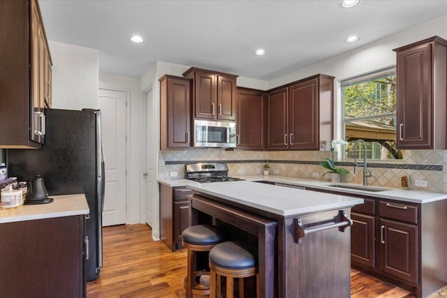 2608 Lightfoot Trl, Austin, TX 78745 - kitchen with stainless steel appliances, wood finished floors, light countertops, backsplash, and recessed lighting