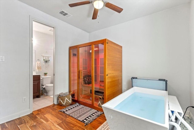 2608 Lightfoot Trl, Austin, TX 78745 - bedroom with wood finished floors, connected bathroom, and a ceiling fan