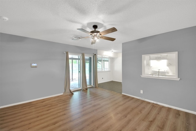 unfurnished room with baseboards, wood finished floors, ceiling fan, and a textured ceiling