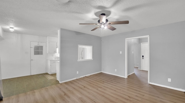 unfurnished room featuring a textured ceiling, light wood-style flooring, baseboards, and a ceiling fan