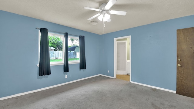 unfurnished room with carpet floors, baseboards, ceiling fan, and a textured ceiling