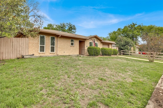 exterior space featuring brick siding, fence, a yard, and an attached garage