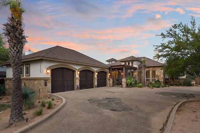 15086 Barrie Dr, Austin, TX 78734 - view of front of home with stone siding, driveway, an attached garage, a chimney, and stucco siding
