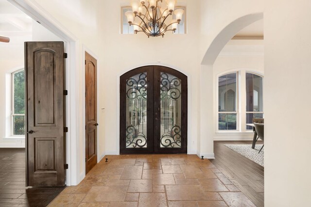 15086 Barrie Dr, Austin, TX 78734 - foyer featuring french doors, a chandelier, arched walkways, baseboards, and a towering ceiling