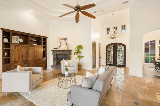 15086 Barrie Dr, Austin, TX 78734 - living room featuring arched walkways, a towering ceiling, ornamental molding, a chandelier, and stone tile floors