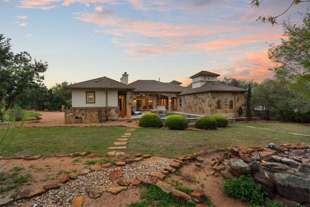 15086 Barrie Dr, Austin, TX 78734 - back of house with stone siding, a patio area, a yard, a chimney, and stucco siding