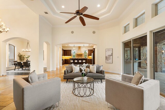 15086 Barrie Dr, Austin, TX 78734 - living room featuring arched walkways, a chandelier, a high ceiling, ornamental molding, and a raised ceiling