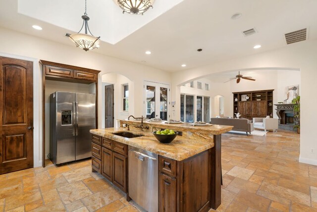 15086 Barrie Dr, Austin, TX 78734 - kitchen featuring appliances with stainless steel finishes, arched walkways, a sink, stone tile flooring, and ceiling fan