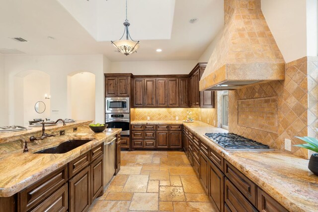 15086 Barrie Dr, Austin, TX 78734 - kitchen featuring stainless steel appliances, a sink, arched walkways, stone tile flooring, and decorative light fixtures
