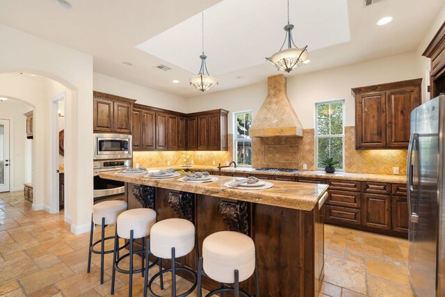 15086 Barrie Dr, Austin, TX 78734 - kitchen with appliances with stainless steel finishes, custom range hood, stone tile floors, arched walkways, and recessed lighting