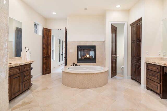 15086 Barrie Dr, Austin, TX 78734 - full bath featuring a garden tub, vanity, toilet, a tiled fireplace, and recessed lighting