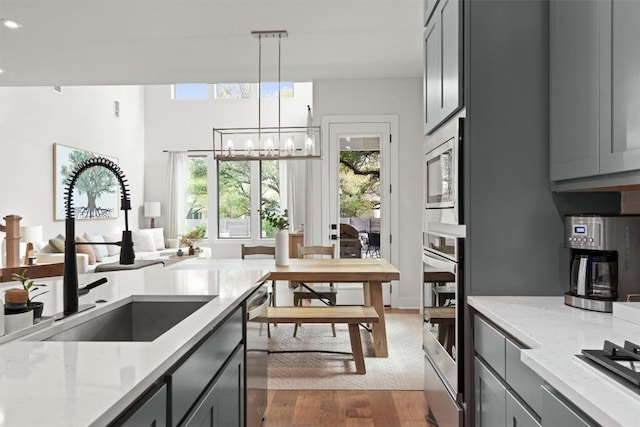 1213 Silver Dollar Trl, Georgetown, TX 78628 - kitchen with a sink, gray cabinetry, stainless steel appliances, a chandelier, and wood finished floors
