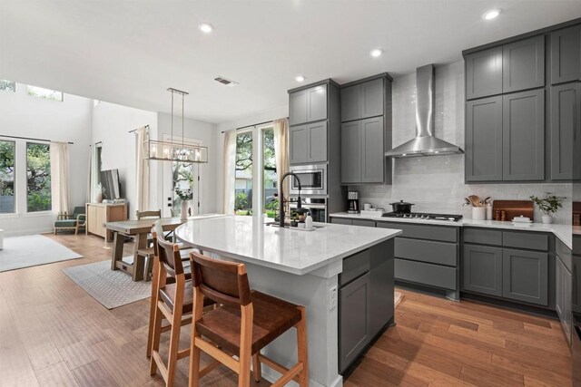 1213 Silver Dollar Trl, Georgetown, TX 78628 - kitchen featuring wall chimney range hood, gray cabinets, tasteful backsplash, recessed lighting, and stainless steel appliances