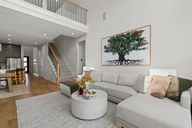 1213 Silver Dollar Trl, Georgetown, TX 78628 - living area featuring stairs, wood finished floors, a towering ceiling, baseboards, and recessed lighting