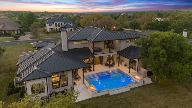 108 Fishspear Ln, Georgetown, TX 78628 - back of house at dusk with a standing seam roof, a balcony, metal roof, a patio, and a lawn
