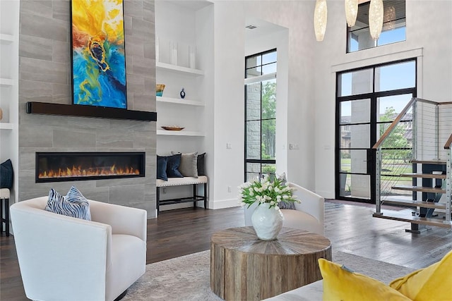 108 Fishspear Ln, Georgetown, TX 78628 - living room featuring wood finished floors, built in features, a tile fireplace, a towering ceiling, and baseboards