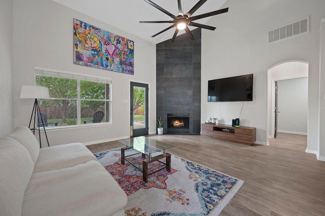 living area with high vaulted ceiling, visible vents, baseboards, wood finished floors, and a ceiling fan