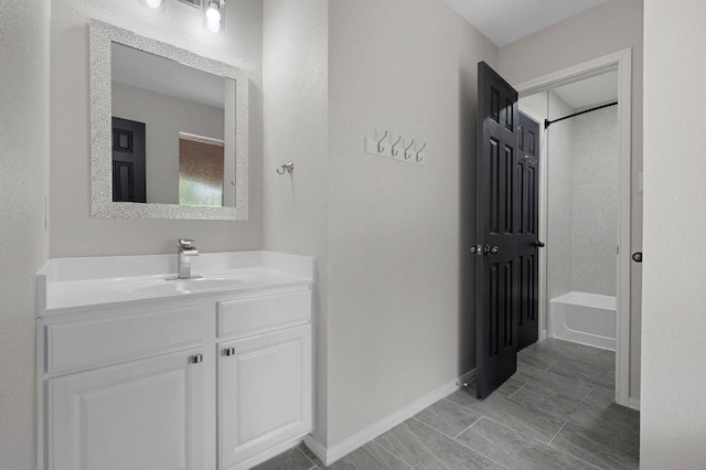 bathroom with baseboards, bathtub / shower combination, and vanity