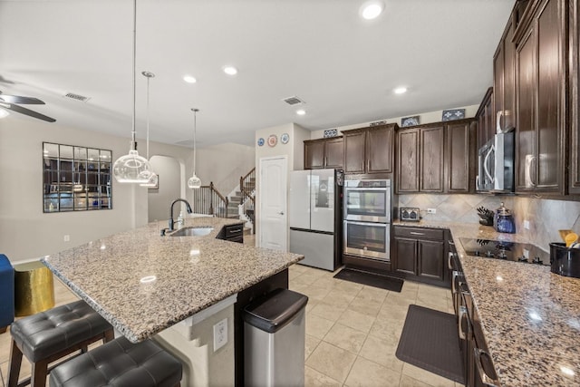 30336 Tiger Woods Dr, Georgetown, TX 78628 - kitchen with appliances with stainless steel finishes, a sink, a kitchen breakfast bar, dark brown cabinetry, and recessed lighting