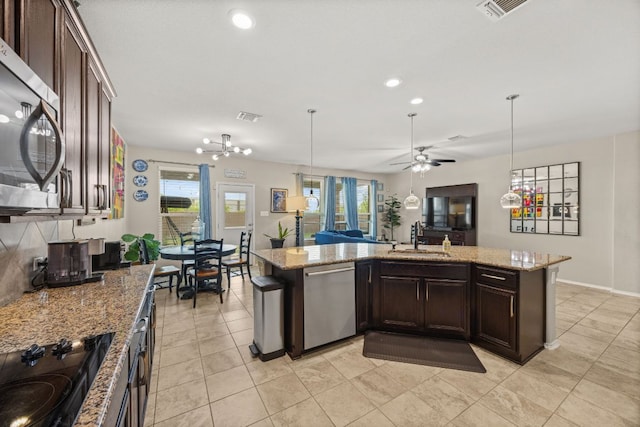30336 Tiger Woods Dr, Georgetown, TX 78628 - kitchen with stainless steel appliances, a sink, dark brown cabinetry, open floor plan, and a ceiling fan