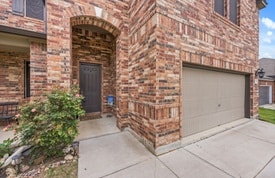 30336 Tiger Woods Dr, Georgetown, TX 78628 - entrance to property with an attached garage, concrete driveway, and brick siding
