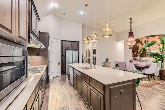 433 Stoney Point Rd, Austin, TX 78737 - kitchen with light wood-style flooring, light countertops, an island with sink, dark brown cabinetry, and recessed lighting