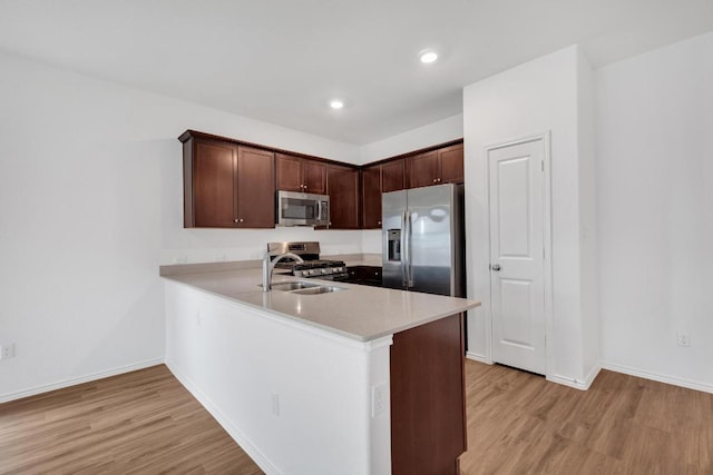 219 George Neggan Ln, Bastrop, TX 78602 - kitchen featuring light countertops, light wood-style flooring, appliances with stainless steel finishes, and a peninsula