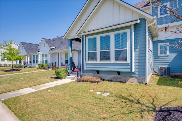 view of front of property featuring cooling unit, board and batten siding, and a front yard