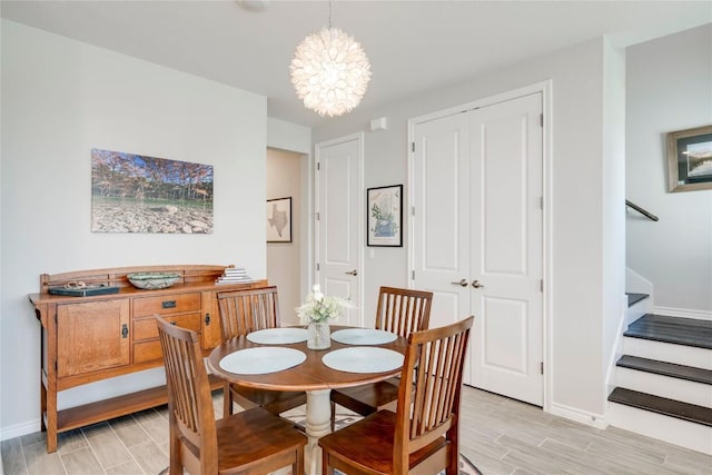 dining room featuring stairs, baseboards, wood finish floors, and an inviting chandelier