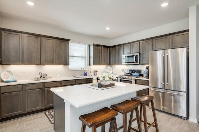 kitchen featuring a sink, stainless steel appliances, dark brown cabinets, and tasteful backsplash