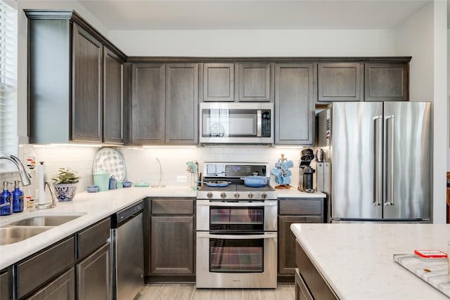kitchen featuring backsplash, dark brown cabinetry, a sink, and stainless steel appliances