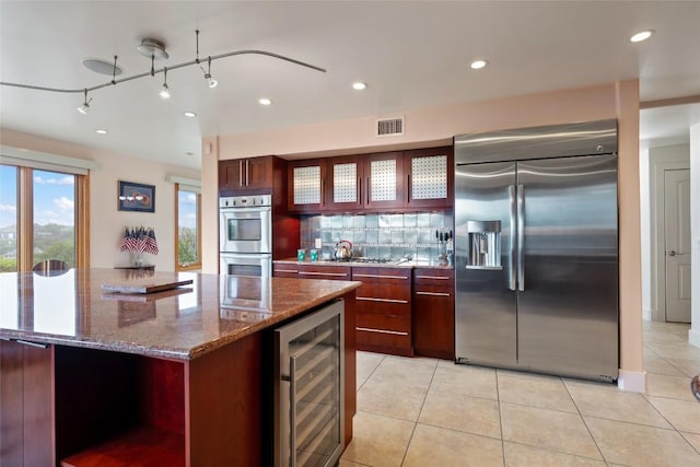 4508 Knapp Holw, Austin, TX 78731 - kitchen with stainless steel appliances, beverage cooler, reddish brown cabinets, and recessed lighting