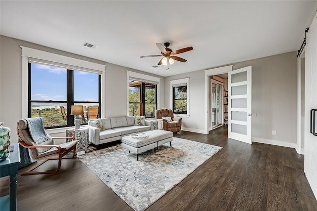 living area with baseboards, visible vents, a ceiling fan, and dark wood-style floors