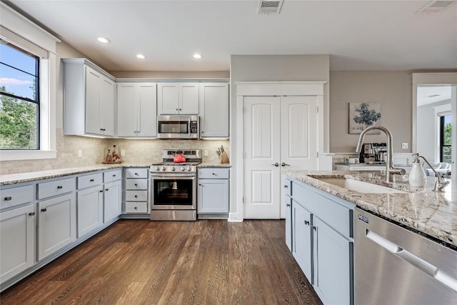 kitchen with a sink, a healthy amount of sunlight, stainless steel appliances, dark wood-style flooring, and visible vents