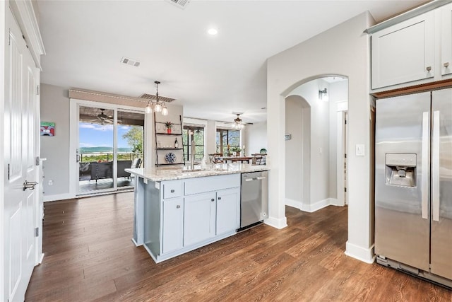kitchen with dark wood-style flooring, ceiling fan with notable chandelier, arched walkways, baseboards, and appliances with stainless steel finishes