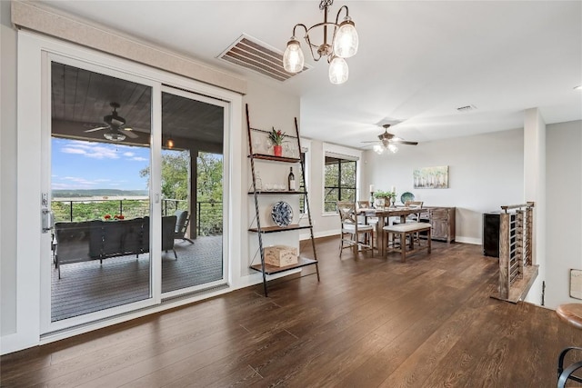 dining space with ceiling fan with notable chandelier, baseboards, visible vents, and hardwood / wood-style floors