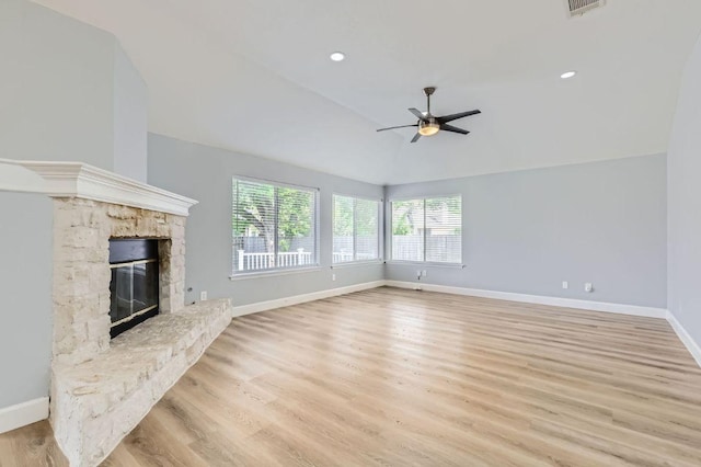 unfurnished living room with a ceiling fan, a stone fireplace, lofted ceiling, light wood-style flooring, and baseboards