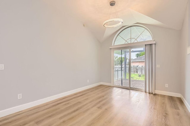 spare room with baseboards, vaulted ceiling, and wood finished floors