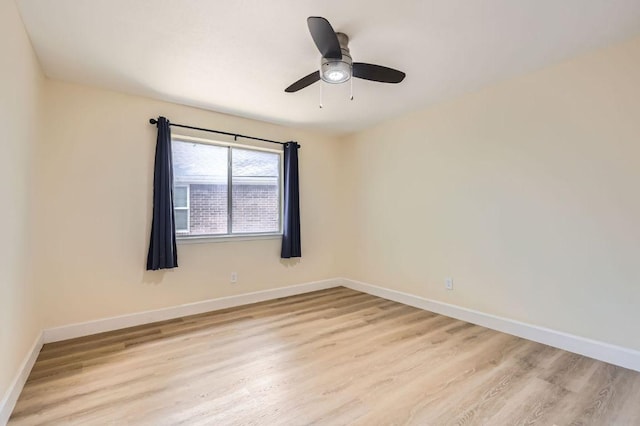 spare room with baseboards, light wood-style flooring, and a ceiling fan