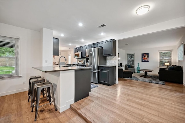 7511 Saint Cecelia St, Austin, TX 78757 - kitchen with stainless steel appliances, a peninsula, a kitchen breakfast bar, a sink, and baseboards